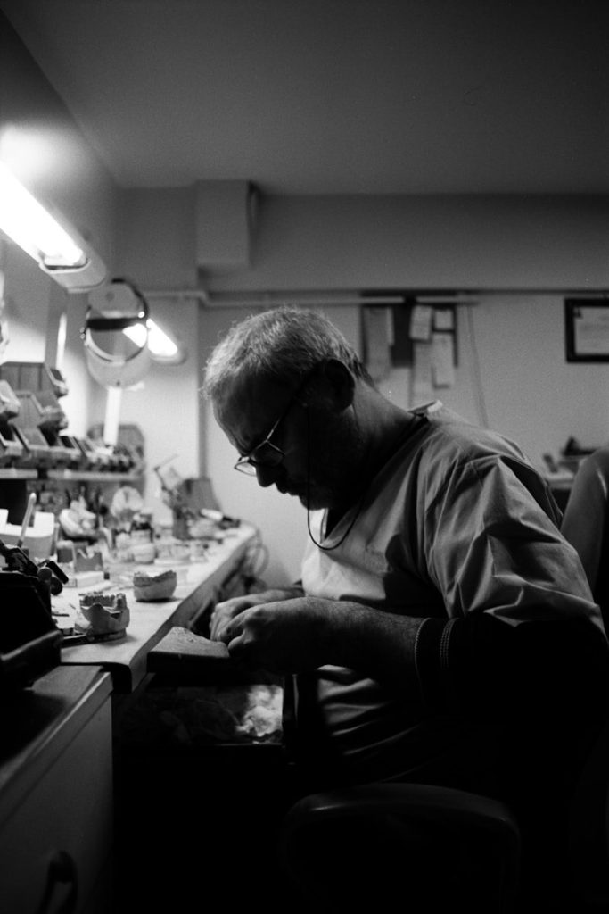 Man working intently at a cluttered workbench.