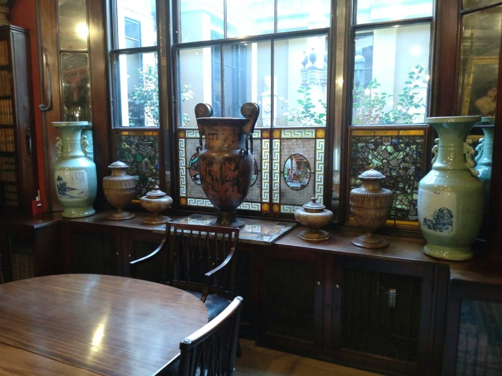 a wooden table sitting next to a window filled with vases