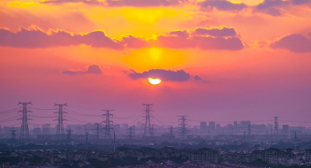 the sun is setting over a city with power lines
