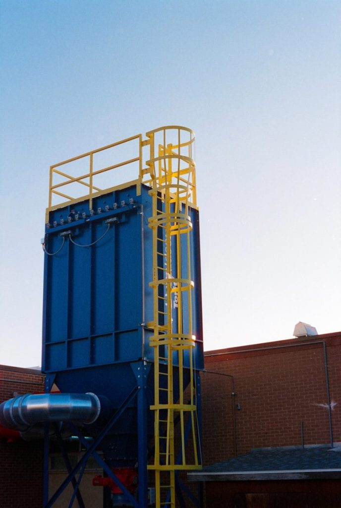 Blue industrial dust collector with yellow ladder