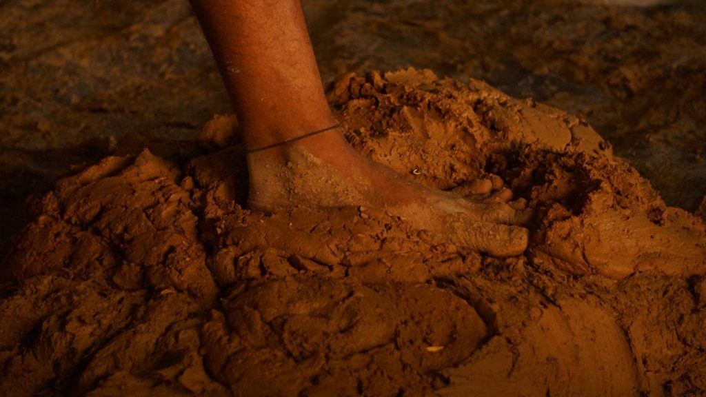 A bare foot is buried in the wet sand.