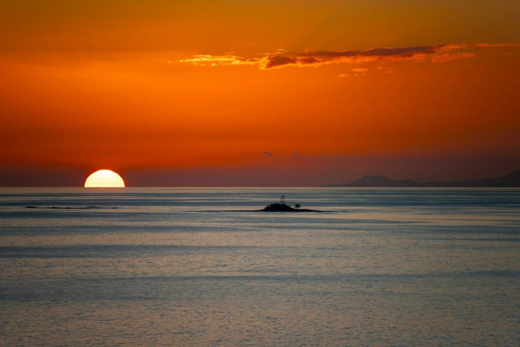a large body of water with a sunset in the background