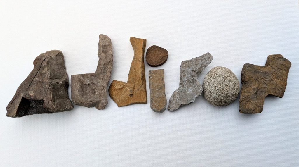 Rocks forming the word 'audition' on a white surface.