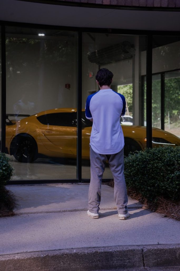 Man looking at a yellow sports car through window