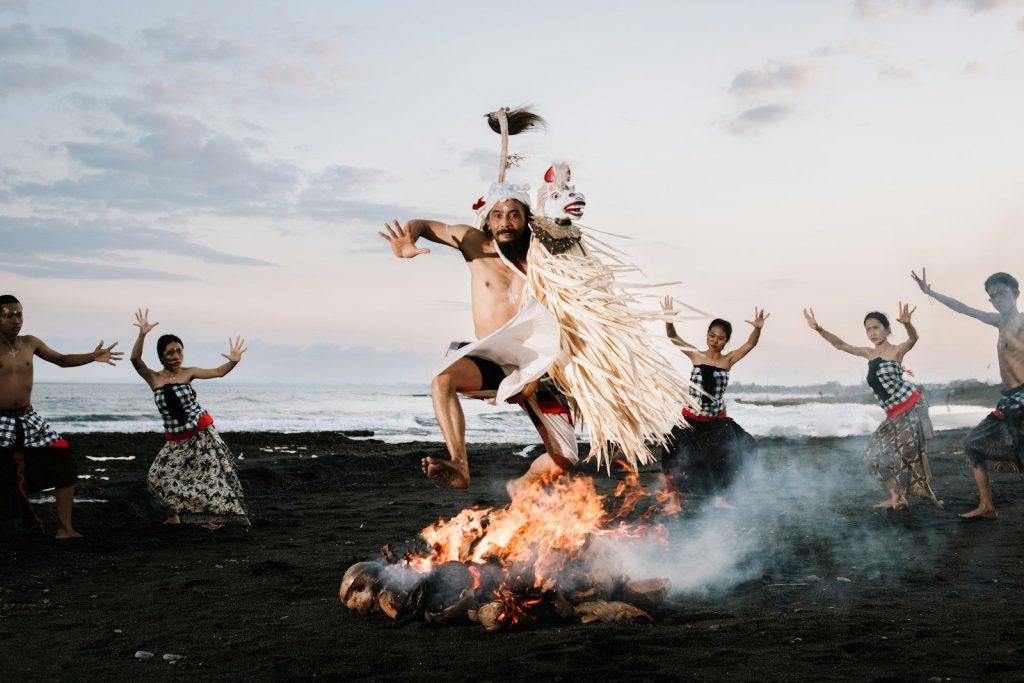 Dancers perform a ritual fire dance on a beach.