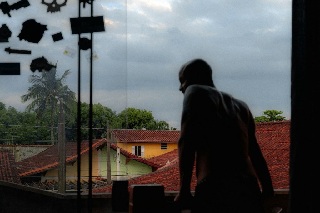 Man looking out window at cloudy sky and rooftops