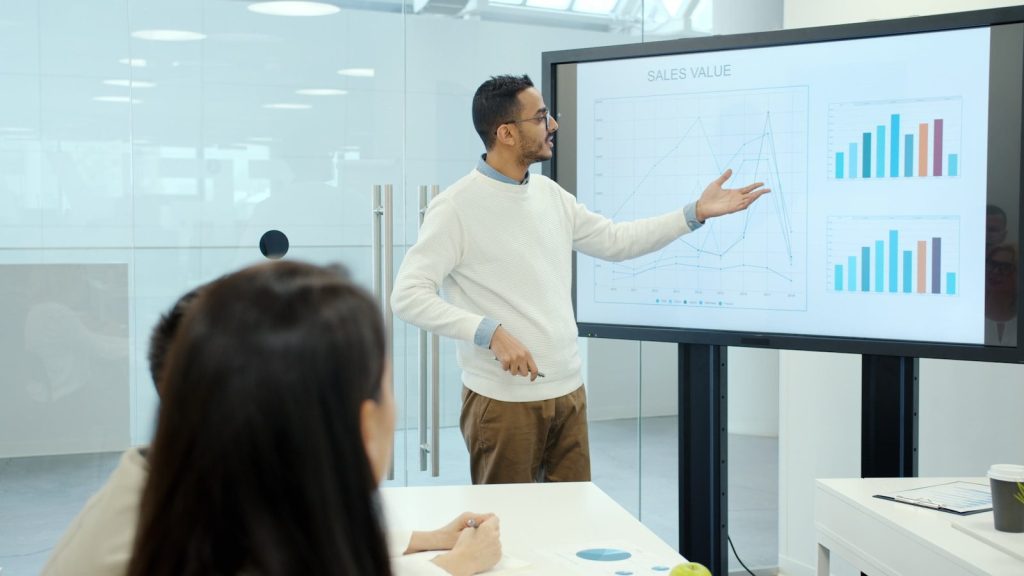 Man presenting charts on a large screen.