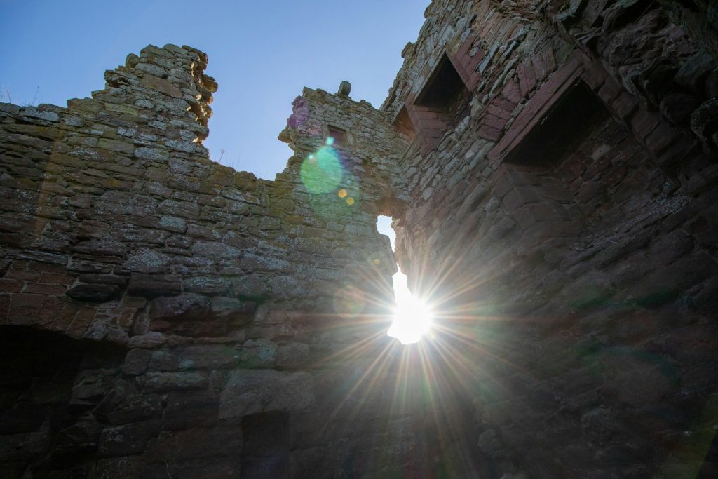 Sunlight streams through a castle's broken walls.