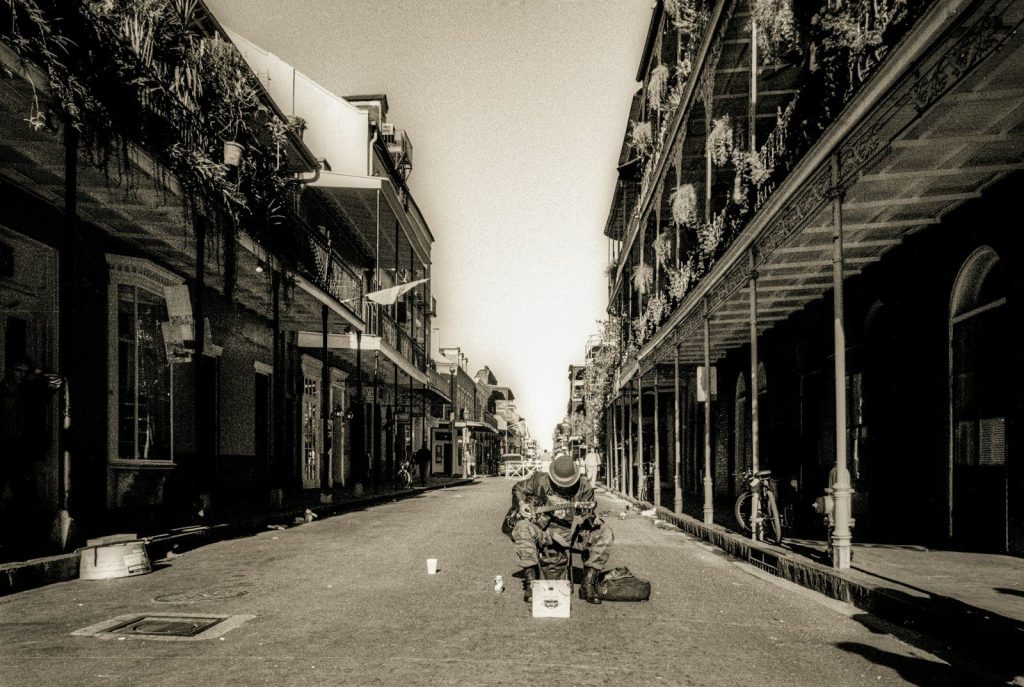 grayscale photo of people walking on street in between buildings