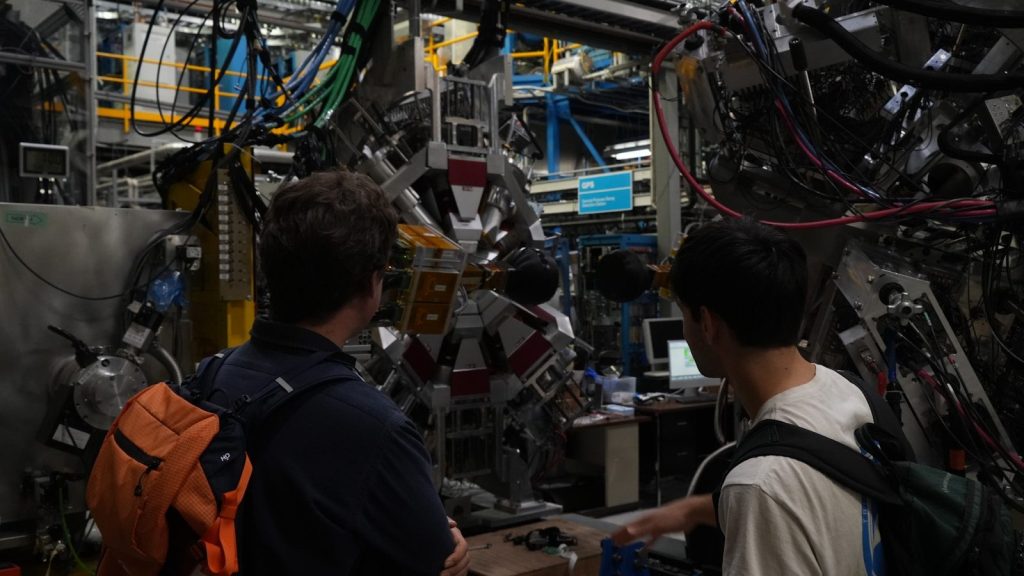 Two people observing complex scientific equipment in a lab.