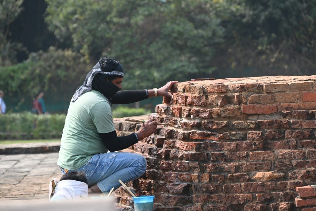 Man repairing ancient brick structure outdoors