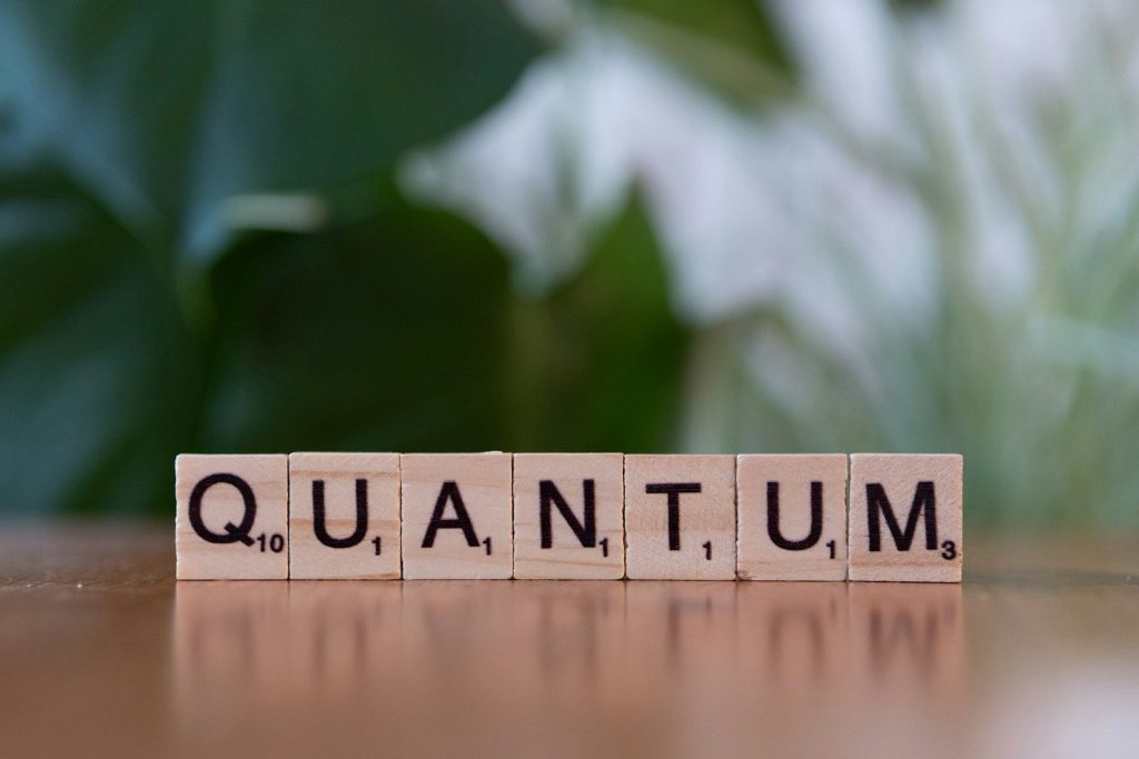 A wooden block spelling the word quanntum on a table