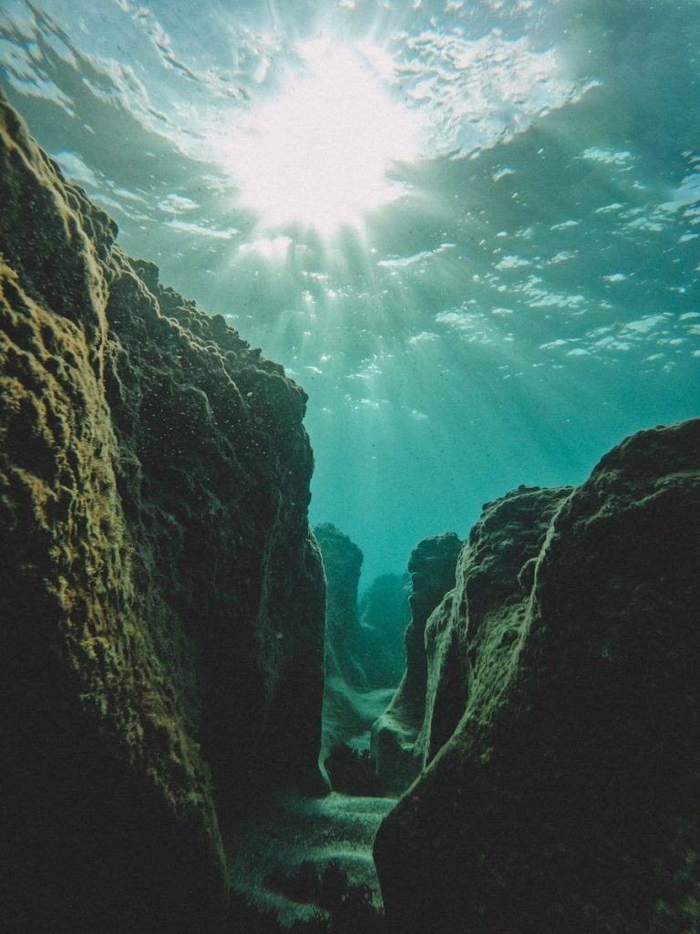 the sun shines through the water over rocks