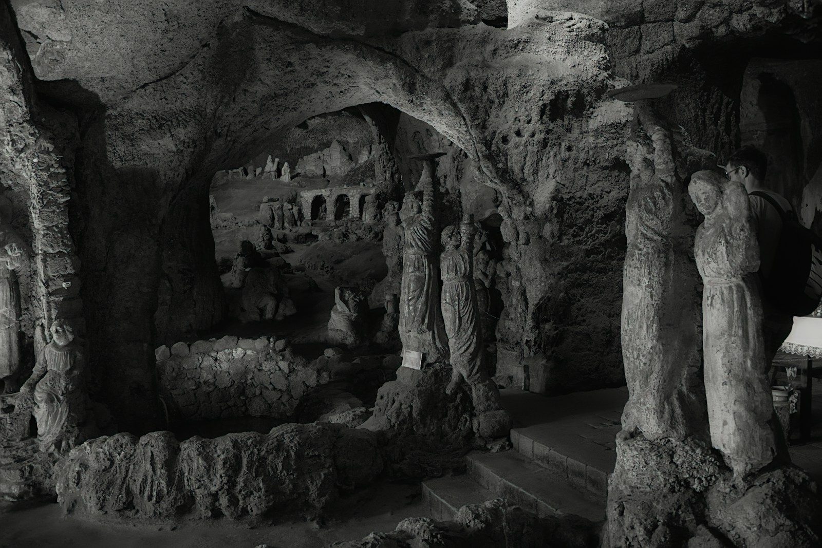 Dark, cavernous interior with rock formations and statues.