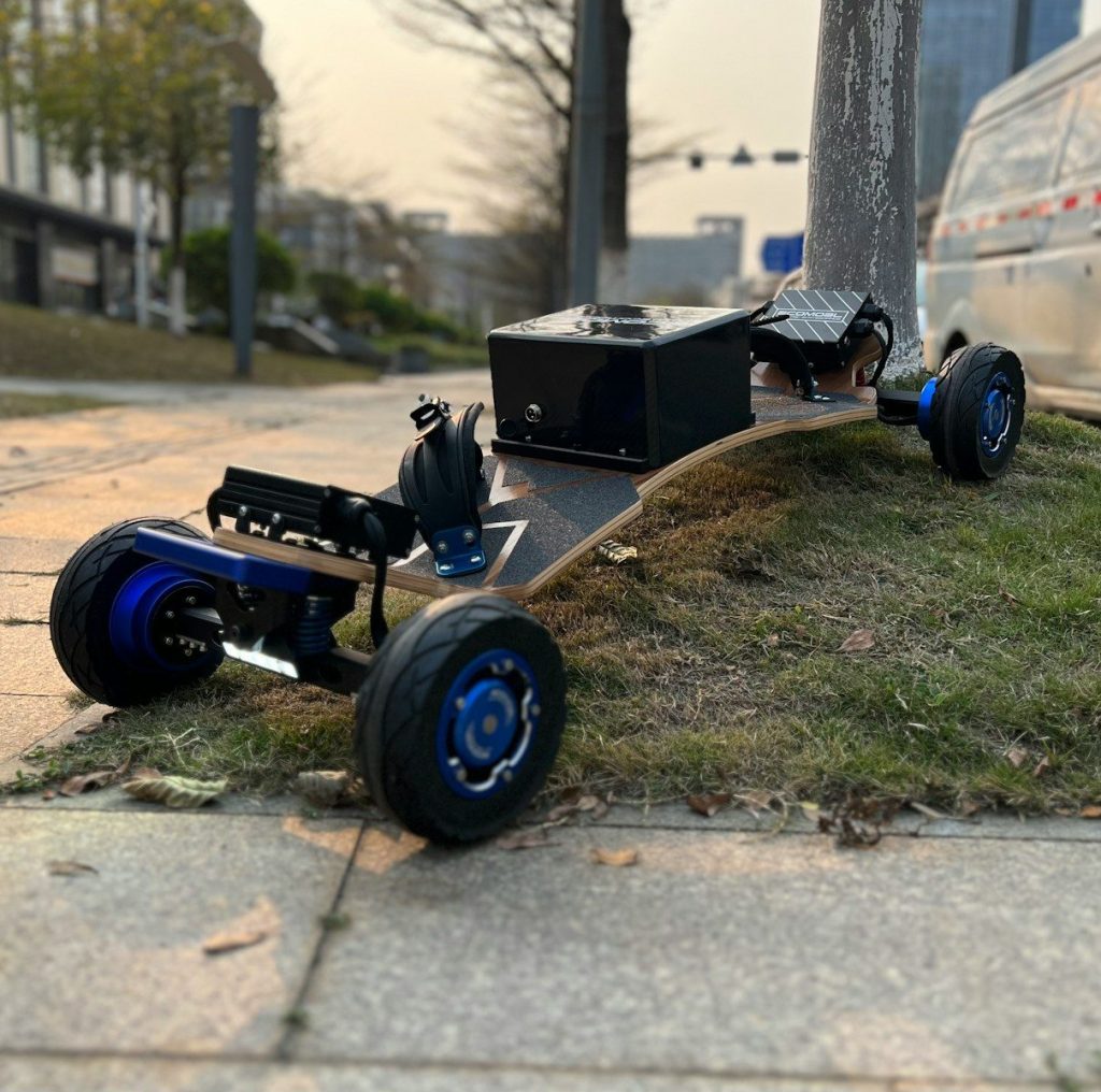 An electric skateboard with large wheels rests on grass.