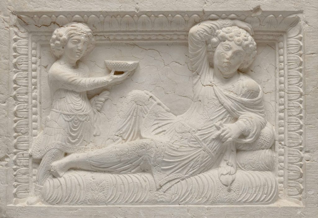 Ancient relief carving of reclining figure and attendant