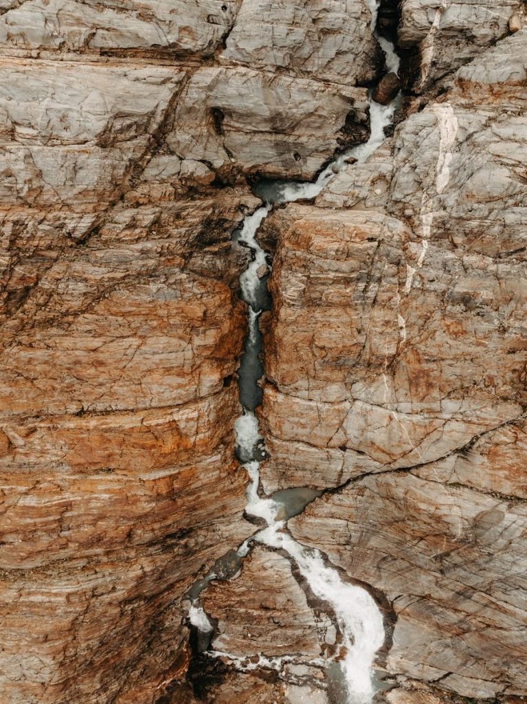 Water flows through a crevice in the rocky cliffside.