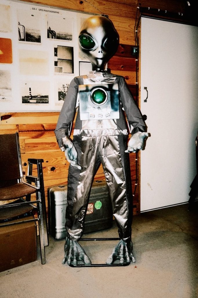 A grey alien mannequin with a camera on its chest.