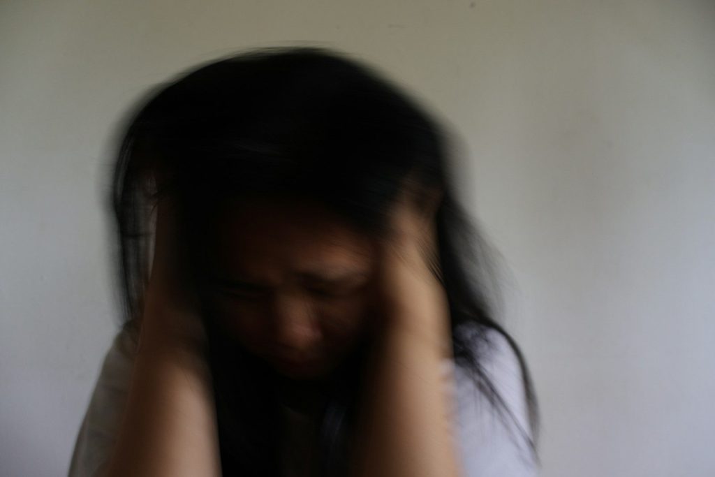 A blurred woman holding her head