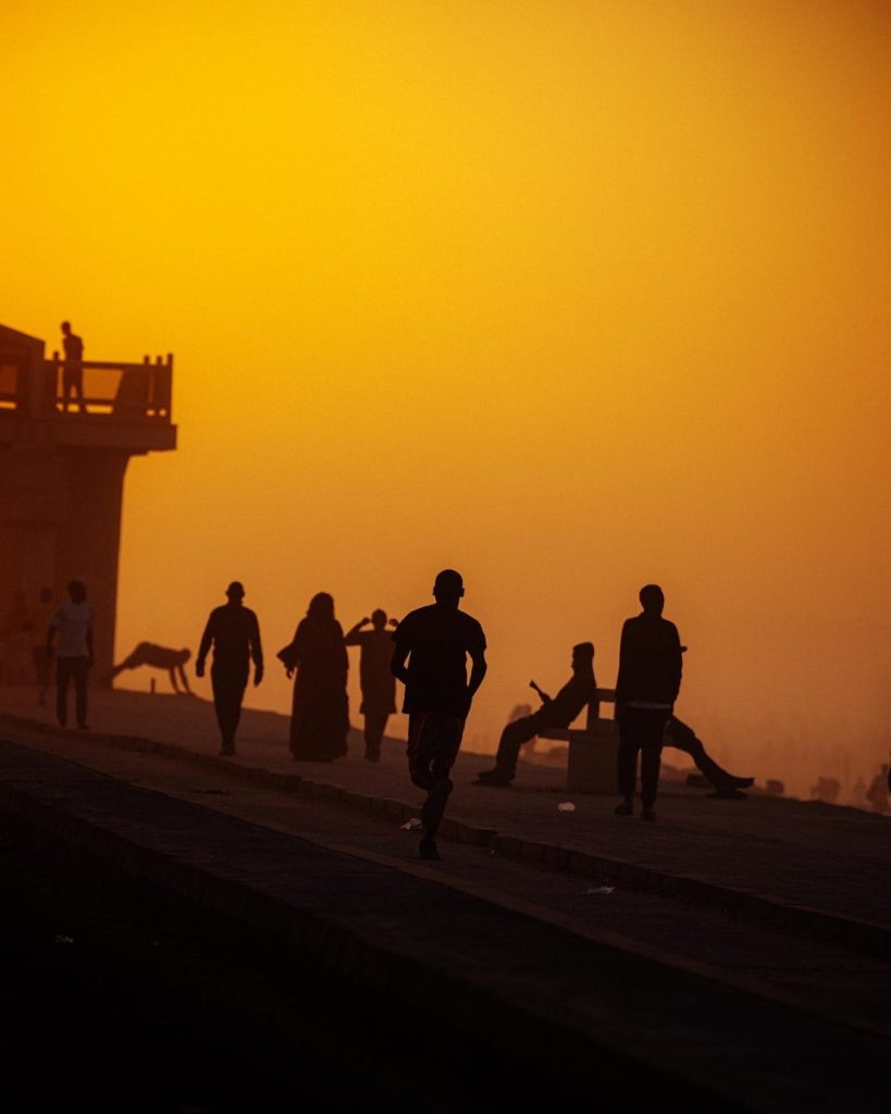 Silhouettes of people walking and running at sunset.