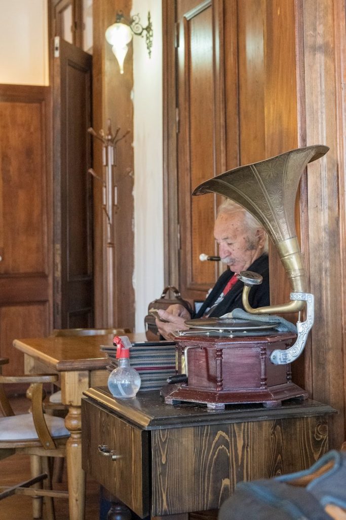 an old man sitting at a table with a trumpet in his mouth