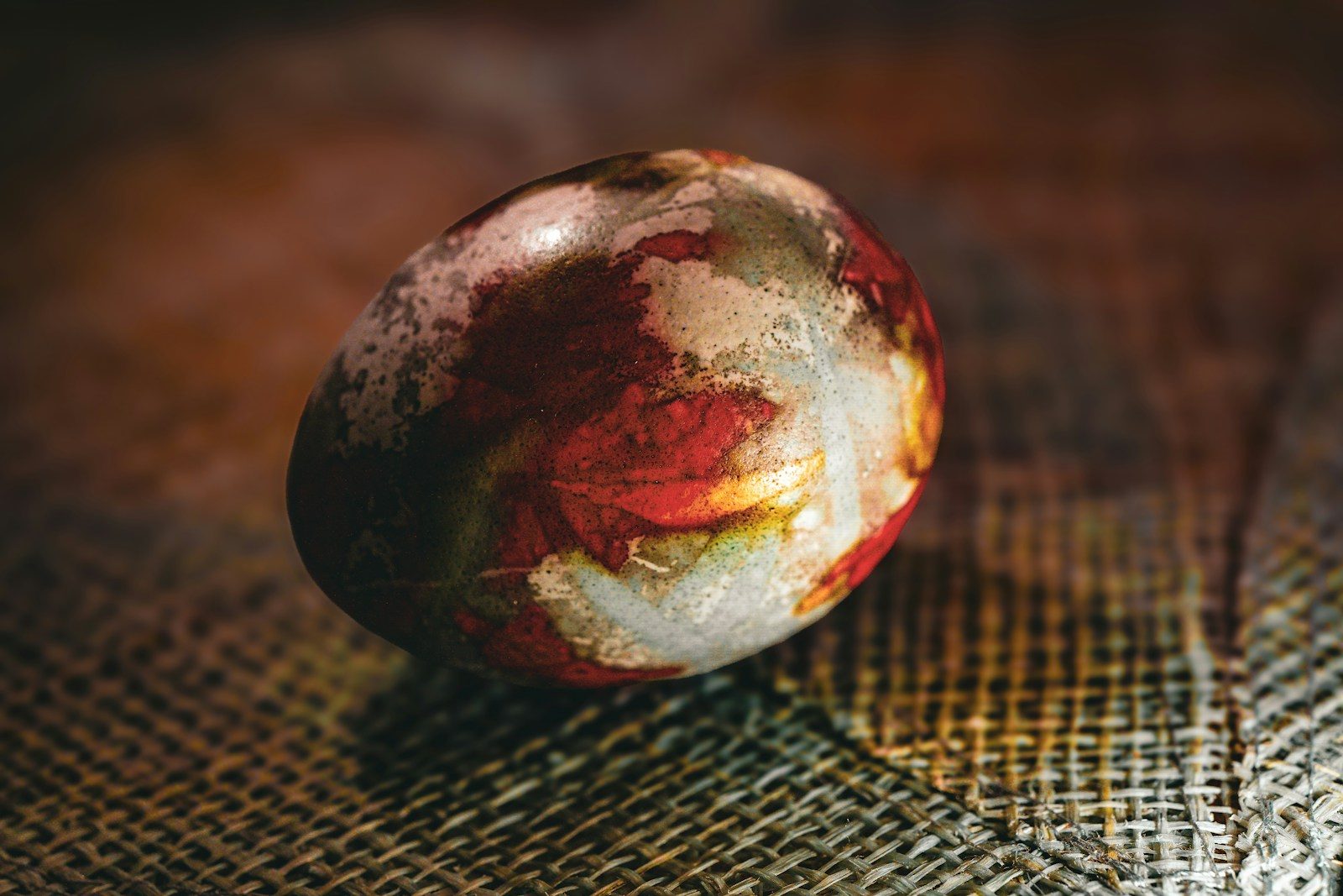 A colorful, patterned stone rests on textured fabric.