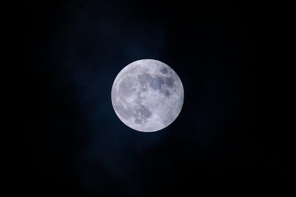 Full moon glowing brightly in the dark night sky.