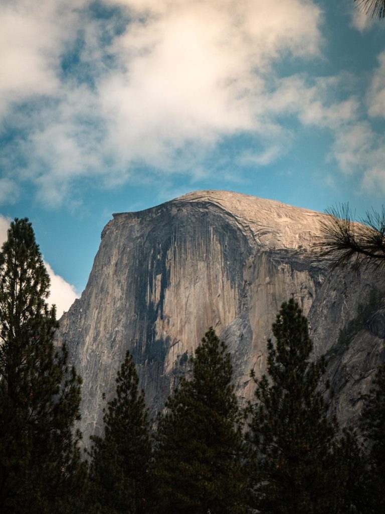 Massive granite rock formation with trees in foreground.
