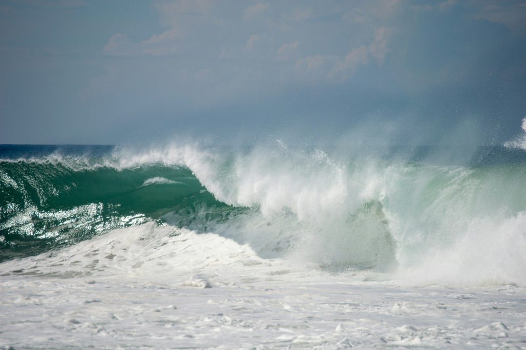 a large wave crashing into the shore of the ocean