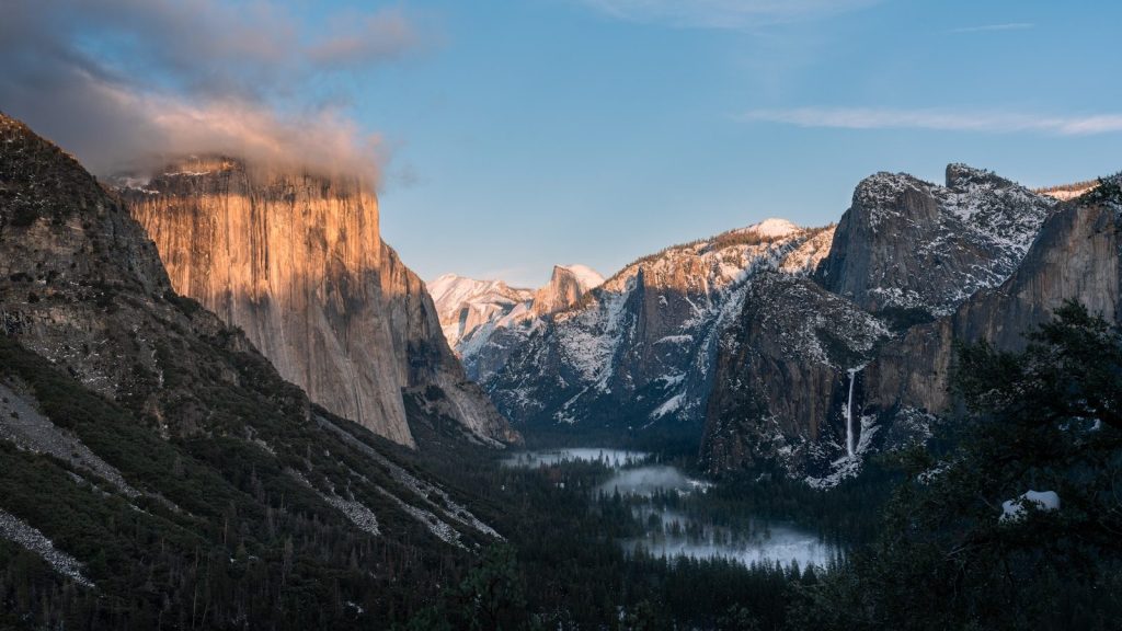 Majestic mountain valley with snow and trees at dawn.