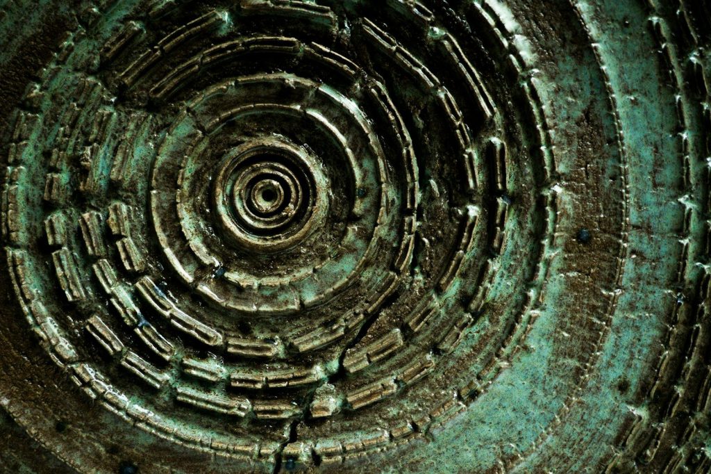 Close-up of a weathered, spiraling metal pattern.