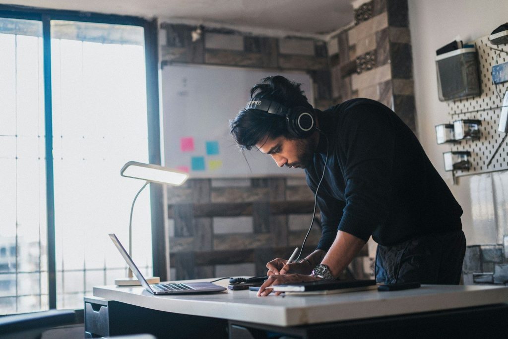 A man works at a desk with headphones.