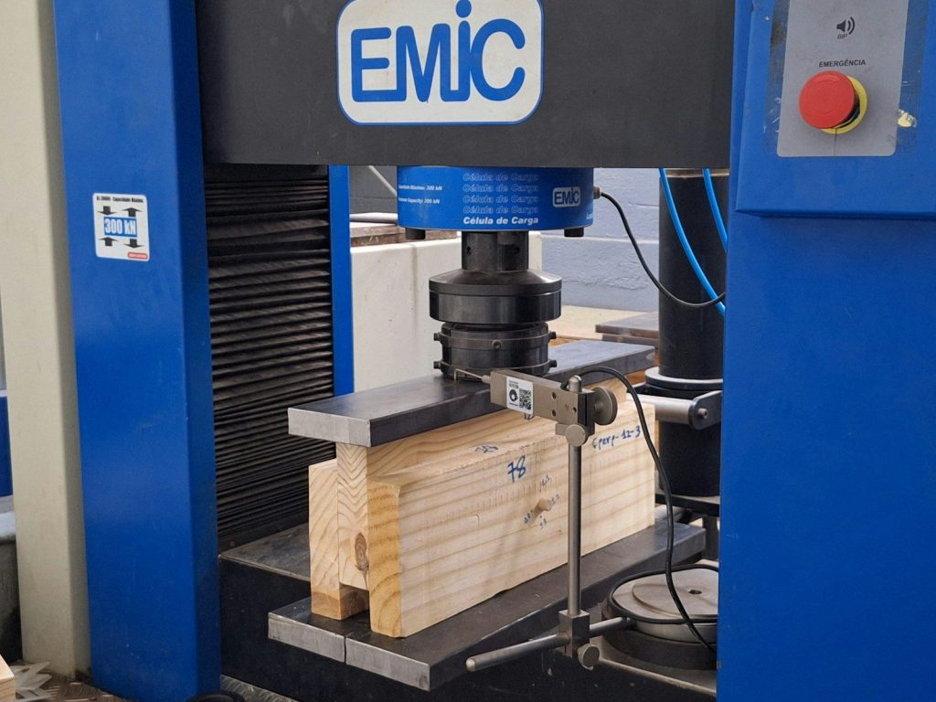 Wood beam undergoing testing in a machine.