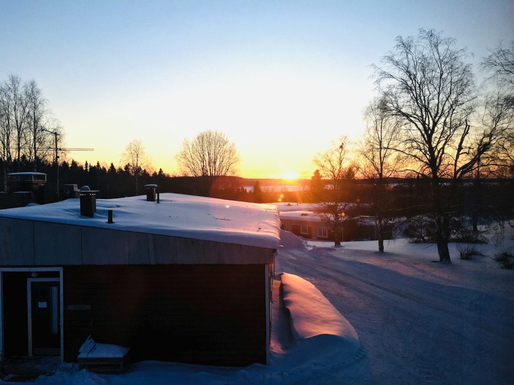 brown wooden house covered with snow during sunset