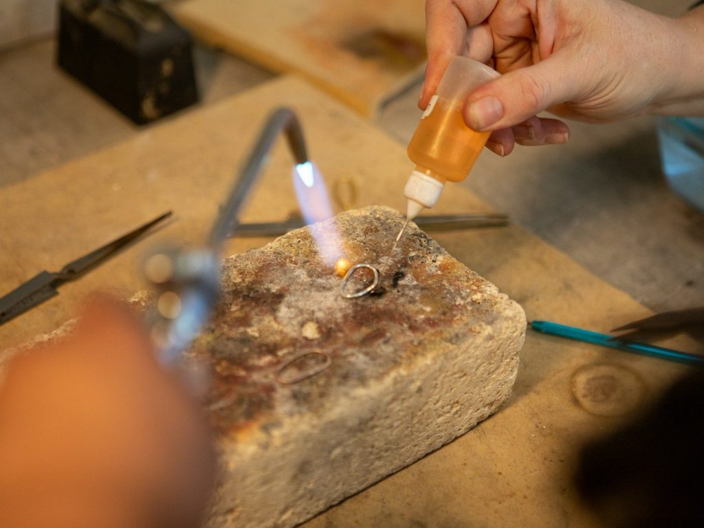 Jeweler soldering a ring with a torch and flux.