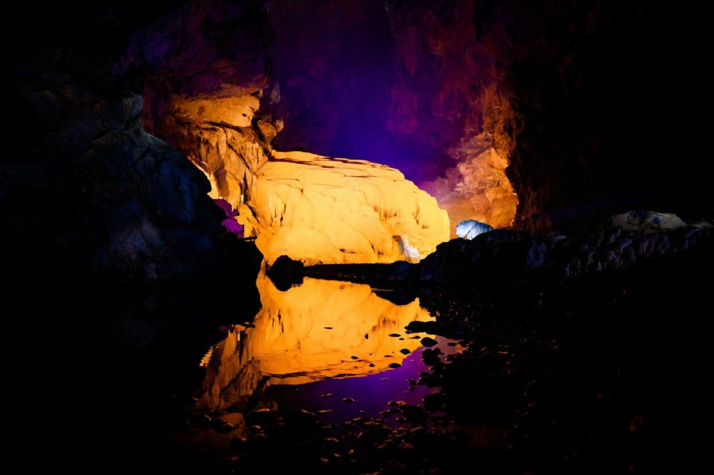 Cave interior with illuminated rock formations and reflection.