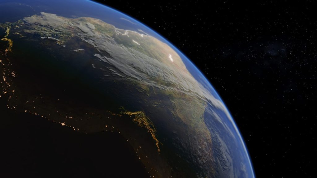 View of earth from space showing landmasses and city lights.