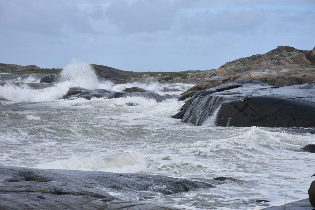 Stormy ocean waves crashing against dark coastal rocks.