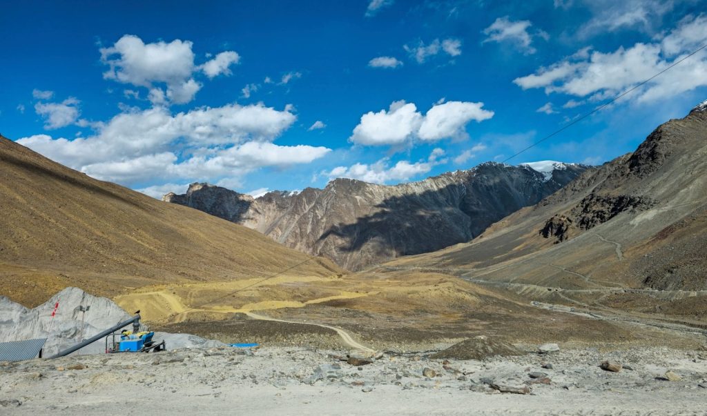 Vast arid mountain valley under a blue sky with clouds.