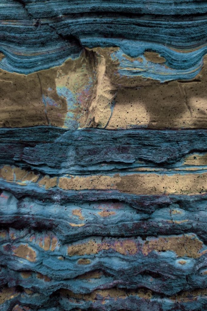 Close-up of layered rock with blue and tan colors.
