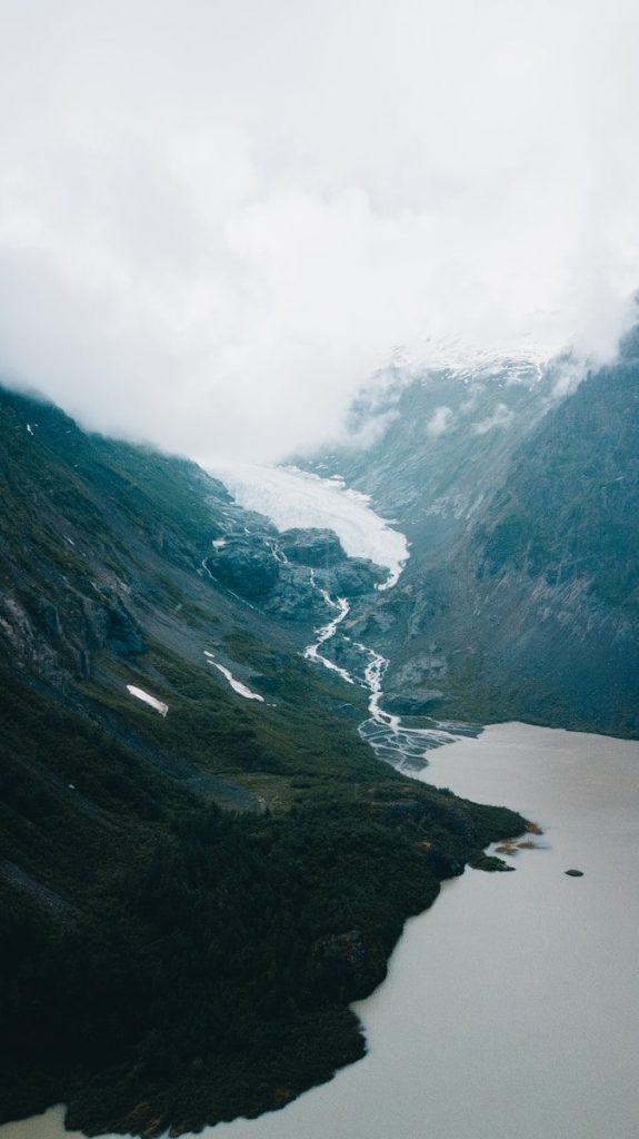 Glacier flowing into a lake surrounded by mountains