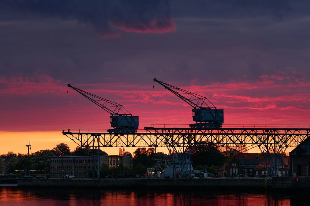 Two cranes silhouetted against a vibrant sunset sky.