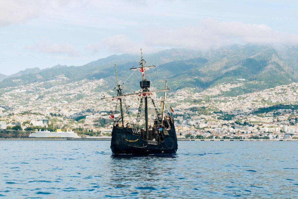 Historic sailing ship on the water with city behind