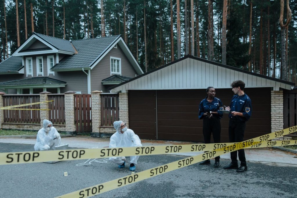 Crime scene investigation in progress outside a suburban house with police officers and forensic experts.
