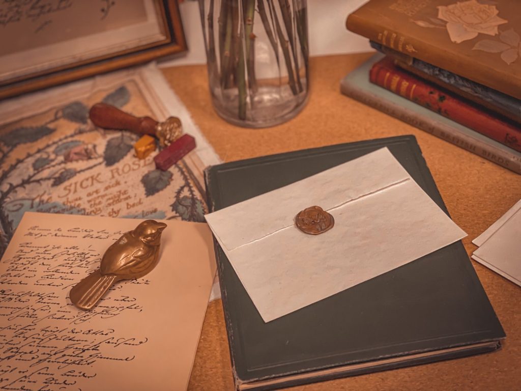 A vintage desk setup featuring a wax-sealed letter, books, and a figurine, evoking a nostalgic and retro atmosphere.