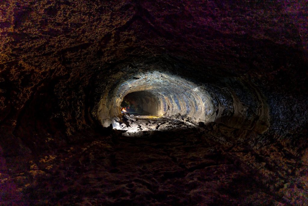 Explore the depths of a cave tunnel with dramatic lighting and intricate textures.