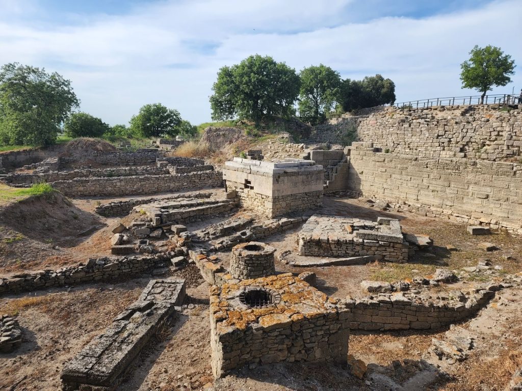 Explore the ancient ruins of Troy in Çanakkale, Turkey, showcasing historical stone structures under a cloudy sky.