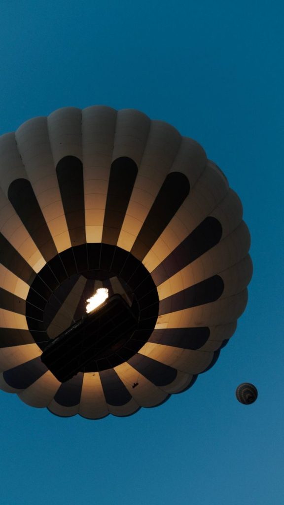A glowing hot air balloon ascends against a clear twilight sky, showcasing nighttime adventure.