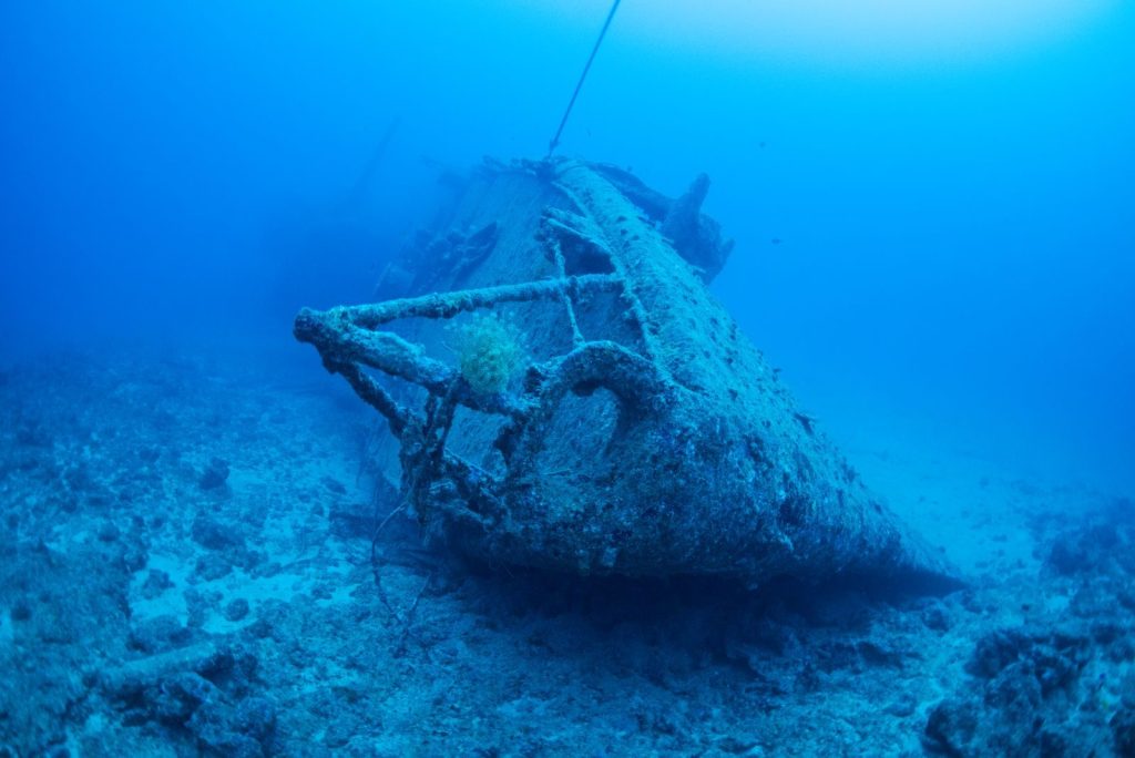 Explore the mysterious beauty of a sunken shipwreck resting on the ocean floor.