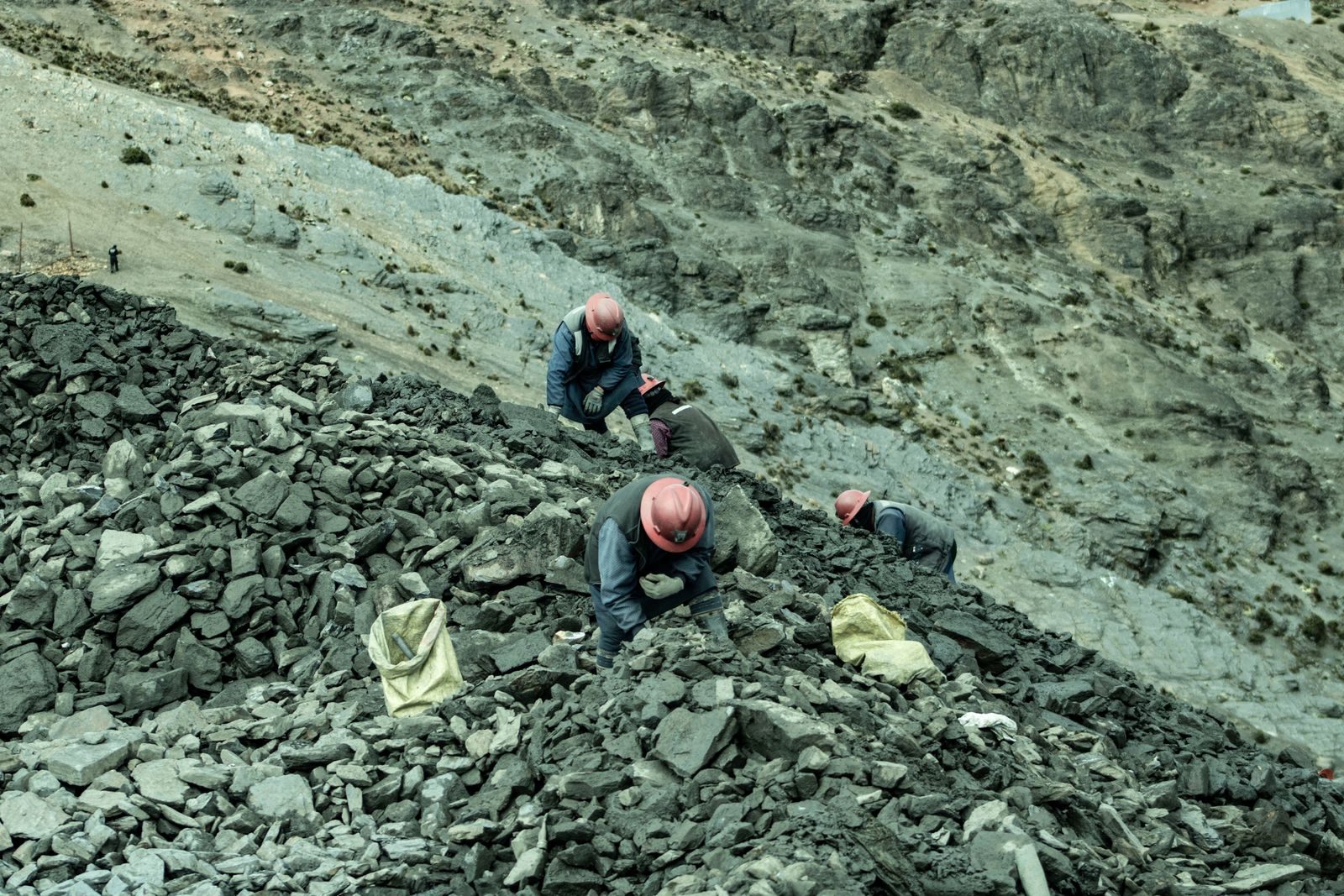 Workers with helmets collecting stones in a rocky quarry, an aerial perspective.